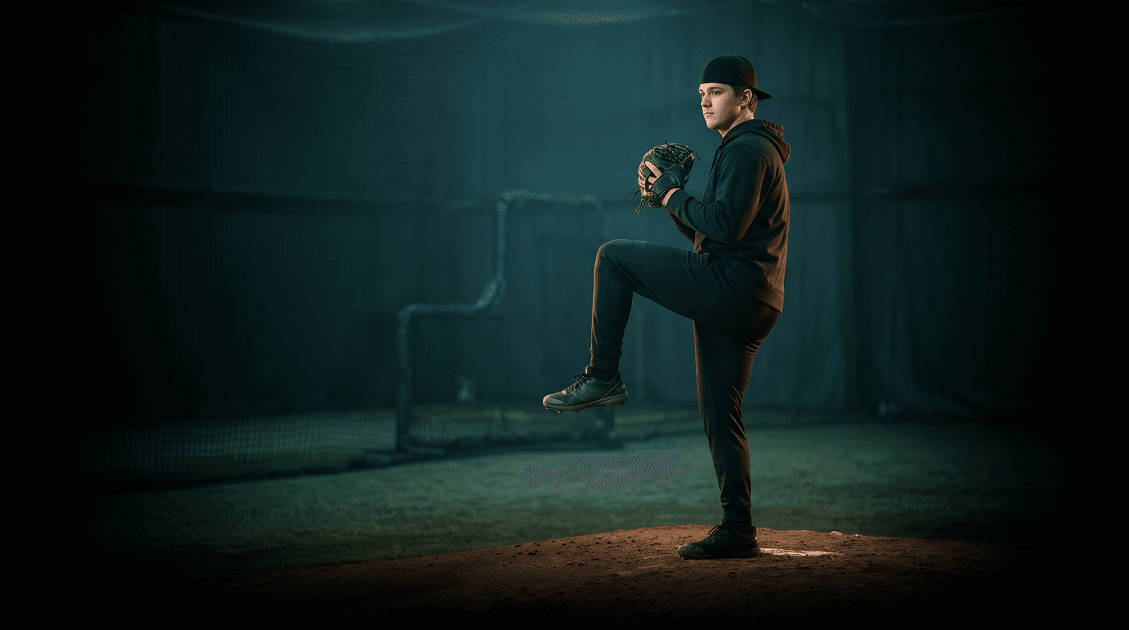 Pitcher at the balance point, illuminated in an indoor pitching facility